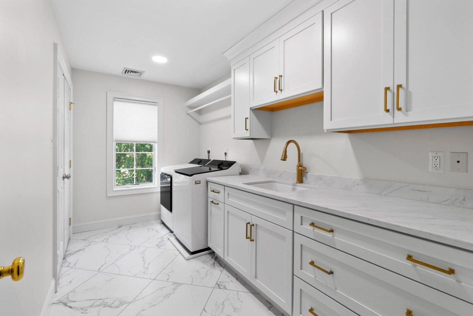 Modern laundry room with white cabinets and washer.