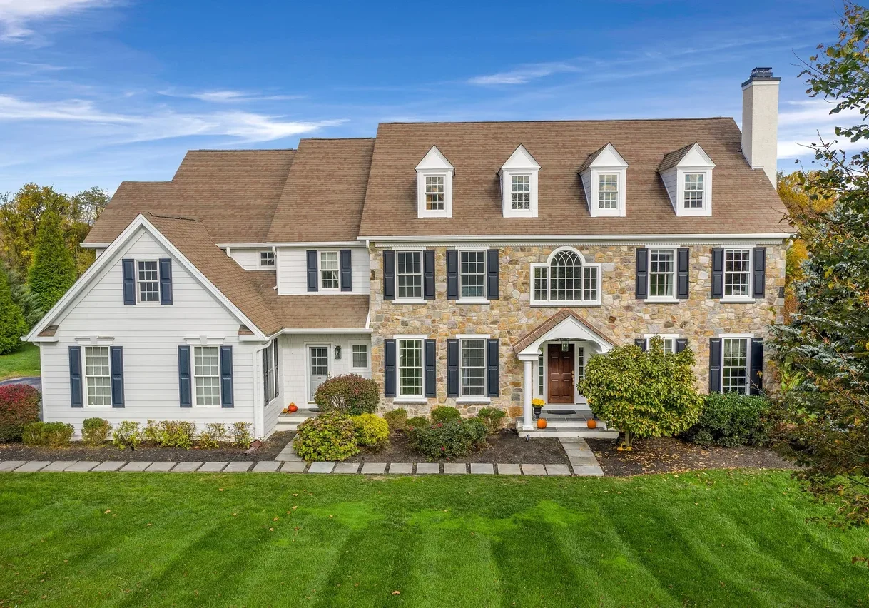 rs=w_1279,m (3) Two-story suburban house with stone and white siding exterior, brown roof, blue shutters, front porch, and landscaped lawn under a blue sky.