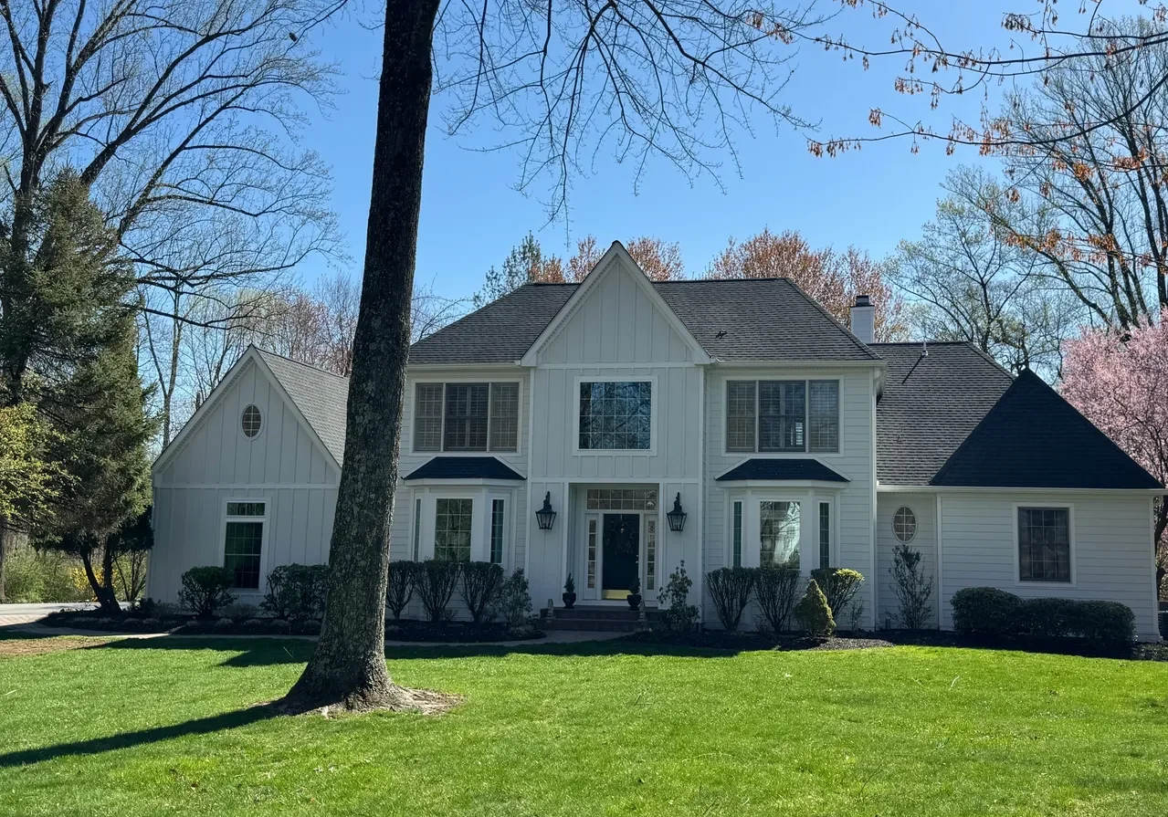 rs=w_1279,m (5) A two-story white suburban house with black roof, large windows, and a well-maintained front lawn, surrounded by trees under a clear blue sky.